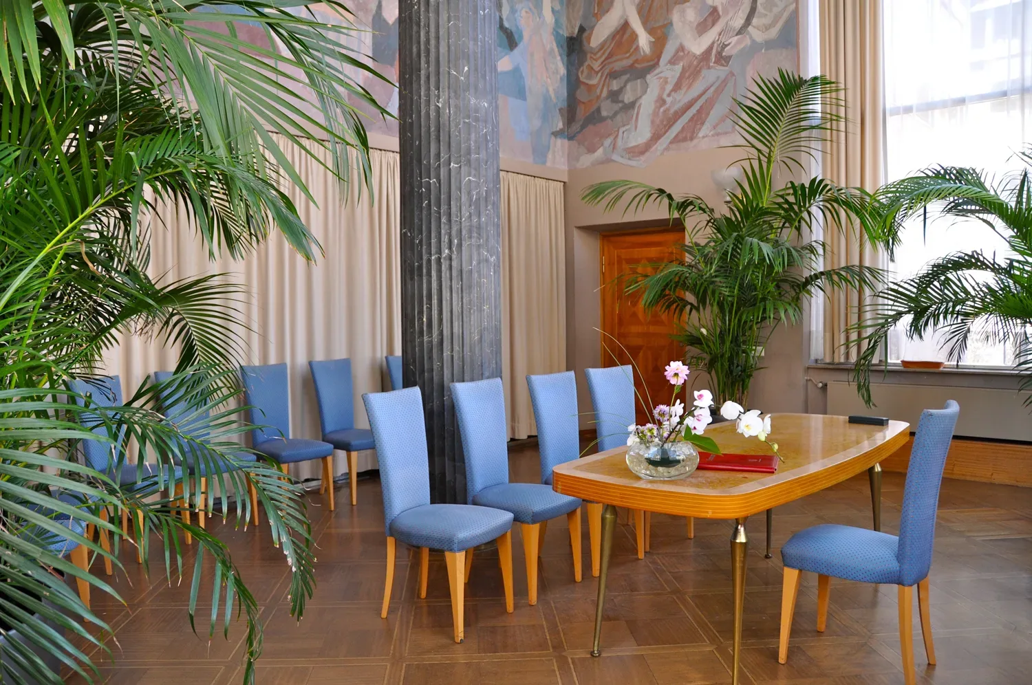 Eleganter Trausaal im Rathaus von Aschaffenburg mit blauen Stühlen und einer natürlichen Dekoration aus Palmen im Hintergrund, bereit für eine standesamtliche Hochzeit.