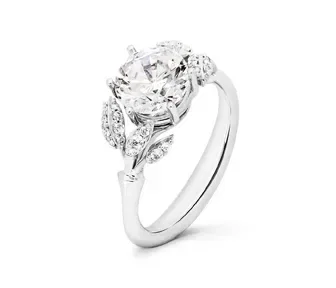 Verlobungsring mit floralem Design, Diamant in Blütenfassung und kleinen Blättern als funkelnde Akzente.