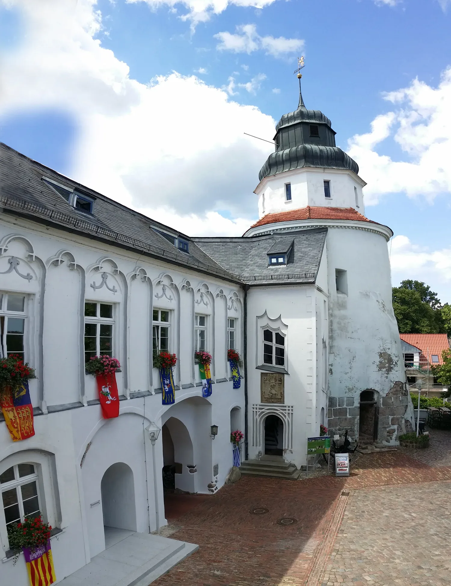 Historisches Schloss mit einem charmanten Innenhof und dekorativen Blumenarrangements an den Fenstern.