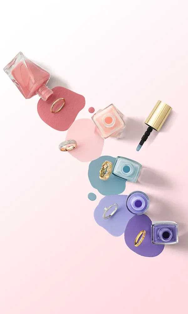 Verschiedene Nagellackfarben mit Eheringen auf rosafarbenem Hintergrund, ideal für Hochzeitsinspirationen.