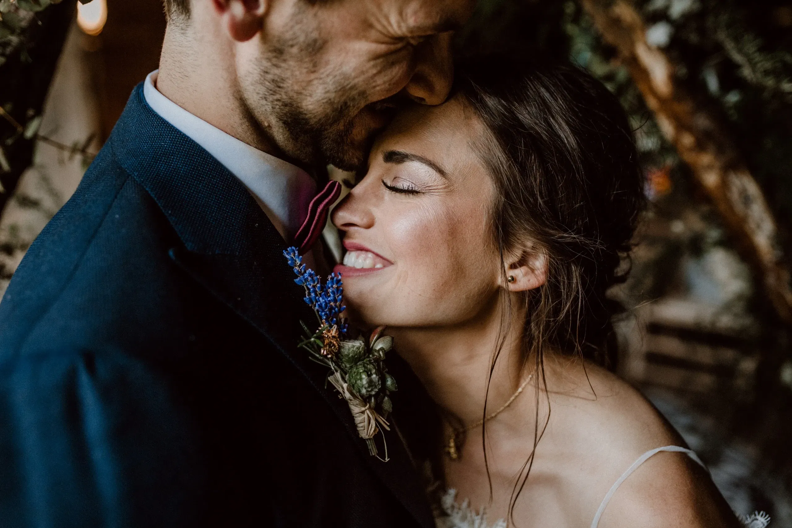 Glückliches Brautpaar in einem zärtlichen Moment, die Braut lächelt liebevoll und lehnt sich an den Bräutigam.