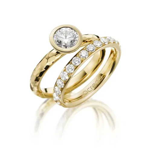 Zwei elegante Gelbgoldringe, einer mit einem großen Diamanten in einer Zargenfassung und der andere mit einem Band aus kleineren Diamanten besetzt. Der Kontrast zwischen dem gehämmerten und glatten Gold verleiht den Ringen einen besonderen Charme.