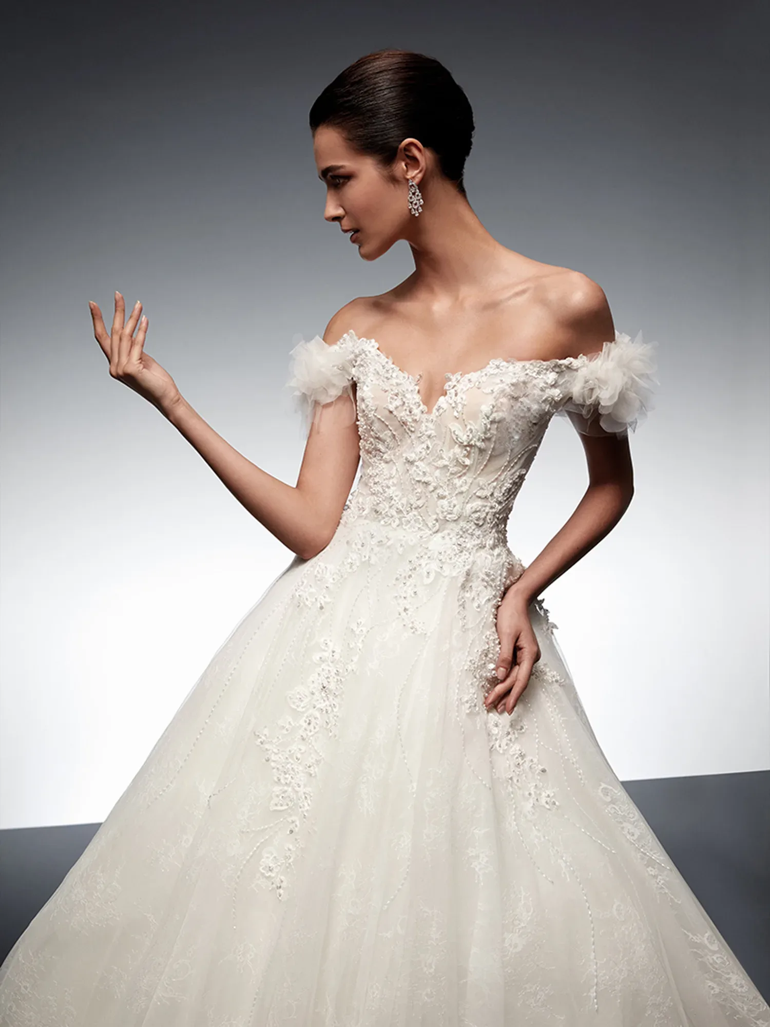 Eine Braut in einem traumhaften Off-Shoulder-Brautkleid aus schimmerndem Tüll und funkelnden Details, perfekt für den großen Hochzeitstag.