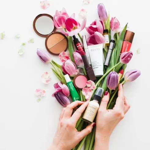 Frühlingshafte Beauty-Produkte und Kosmetika zwischen lilafarbenen Tulpen – ein Arrangement für frische und strahlende Brautlooks.
