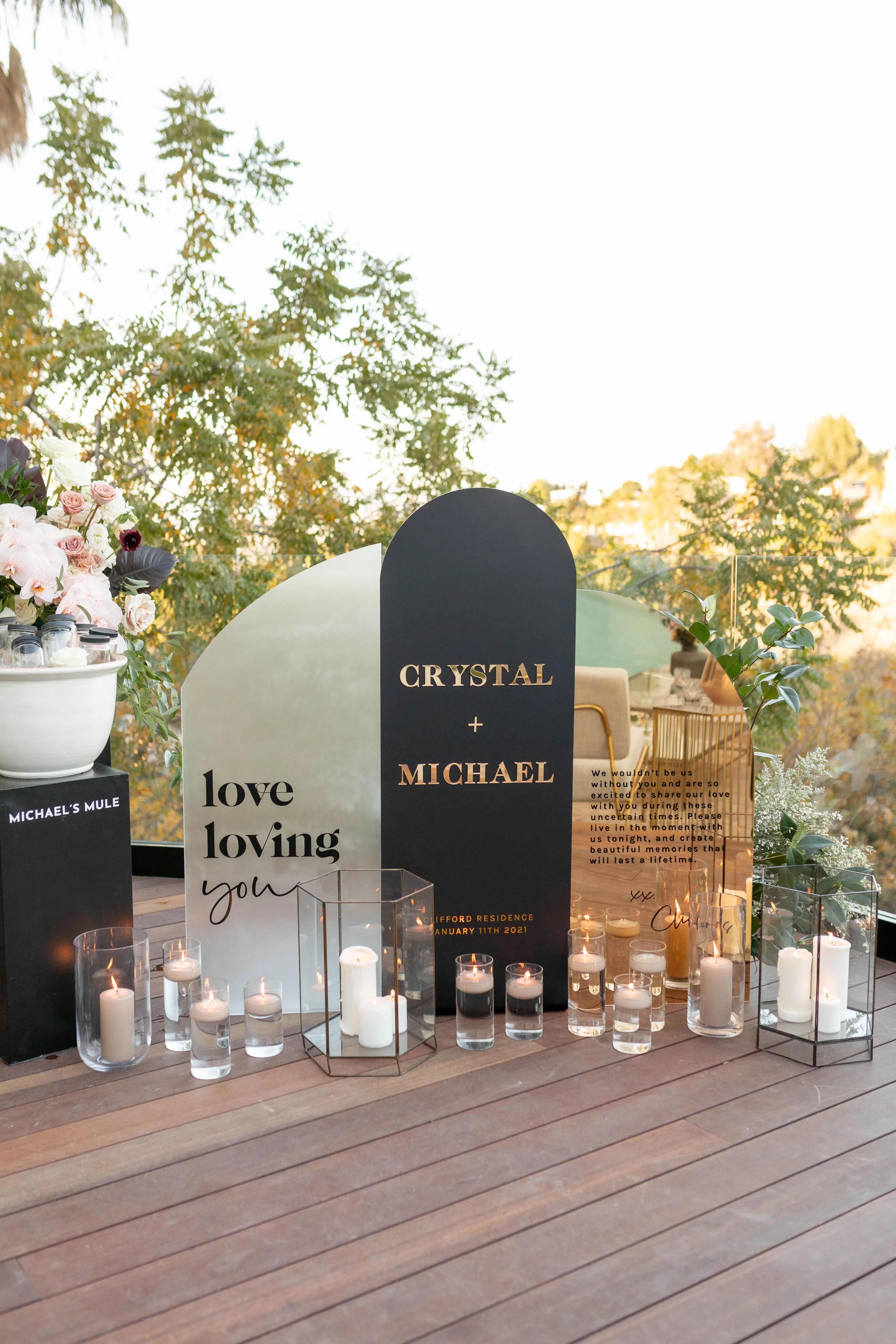 Ein stilvoll dekoriertes Willkommensschild bei einer Hochzeit mit den Namen Crystal und Michael, umgeben von Kerzen und Blumenarrangements.