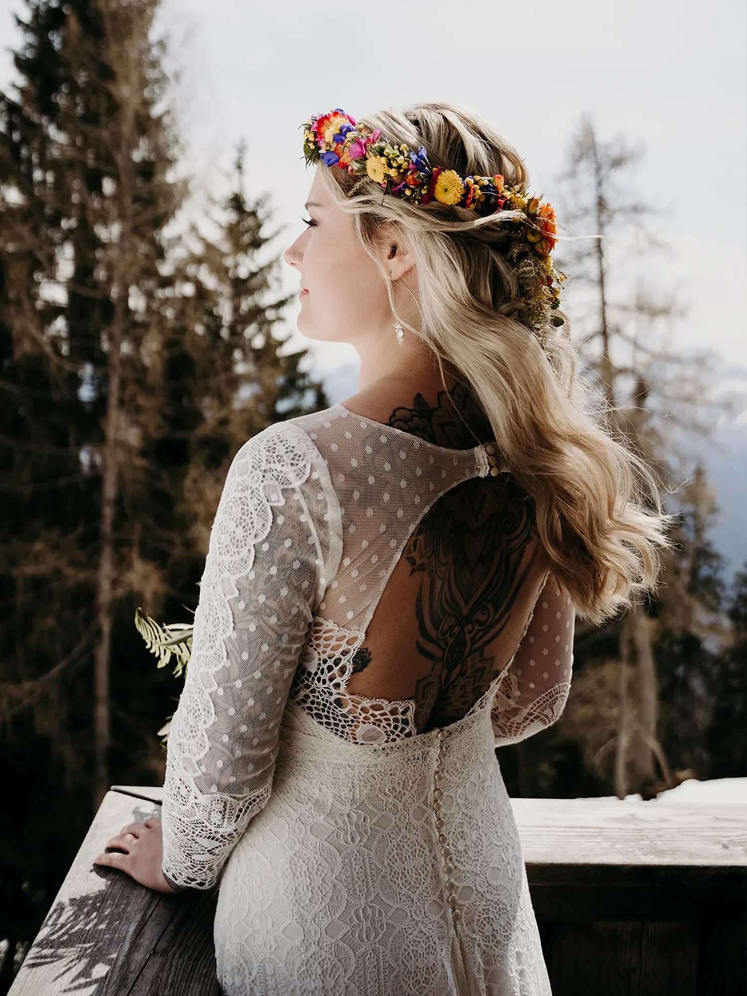 Braut mit Blumenkranz im Haar auf einem Balkon vor Wald