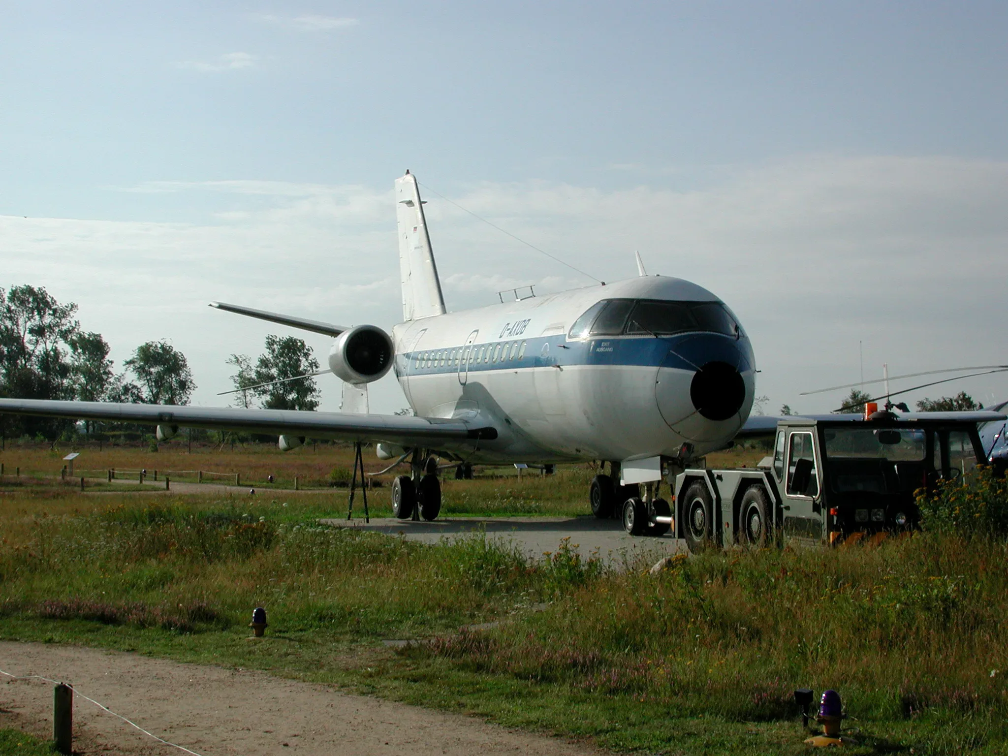 Eine ausgemusterte VFW 614, ein Verkehrsflugzeug, steht auf einem Freiluftmuseumsgelände, umgeben von Wiesen und Bäumen, mit einem Schlepperfahrzeug im Vordergrund.