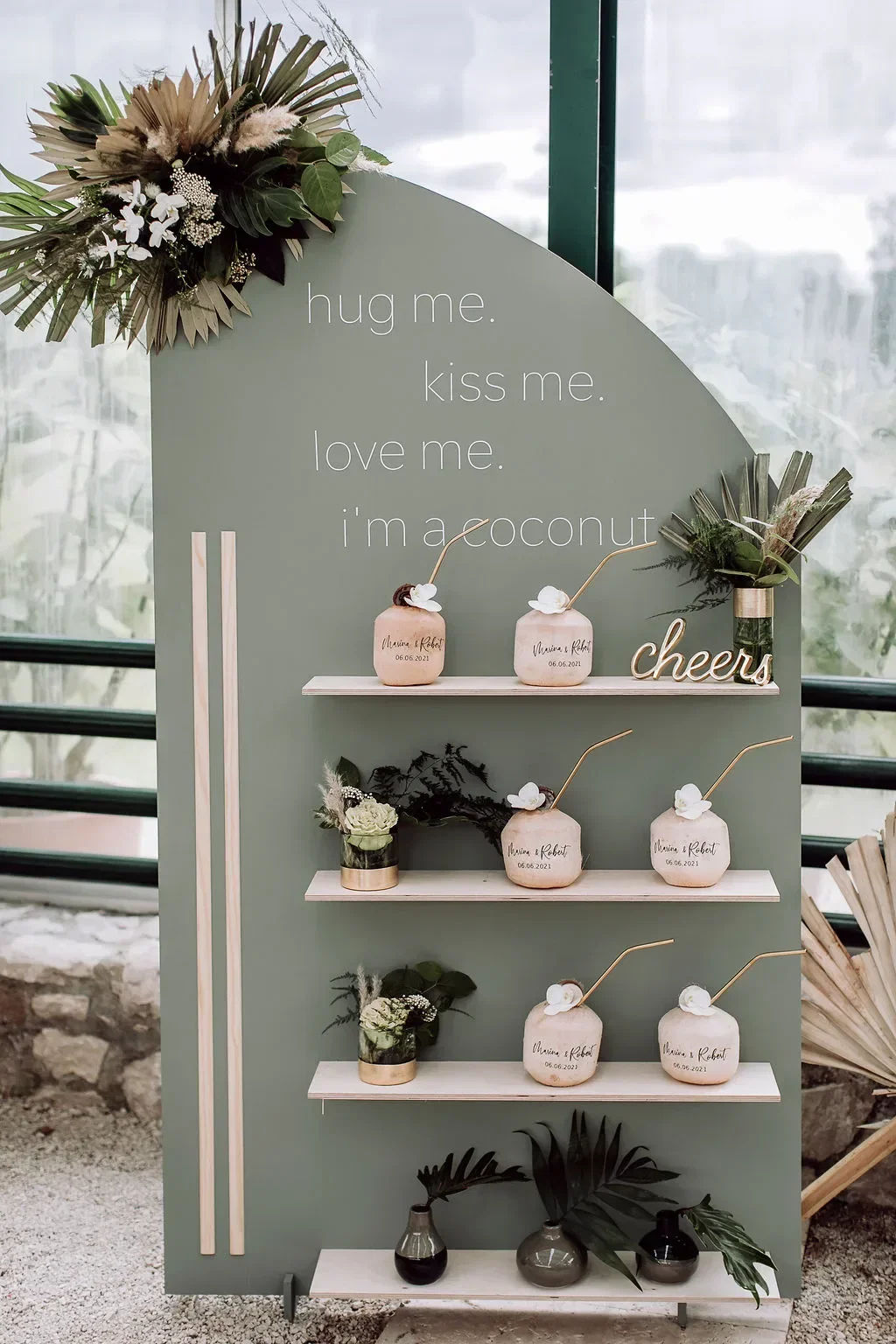Stilvolle Hochzeitsbar mit personalisierten Kokosnüssen, dekoriert mit tropischen Blumen und Pflanzen, passend zur Bali-Hochzeit.