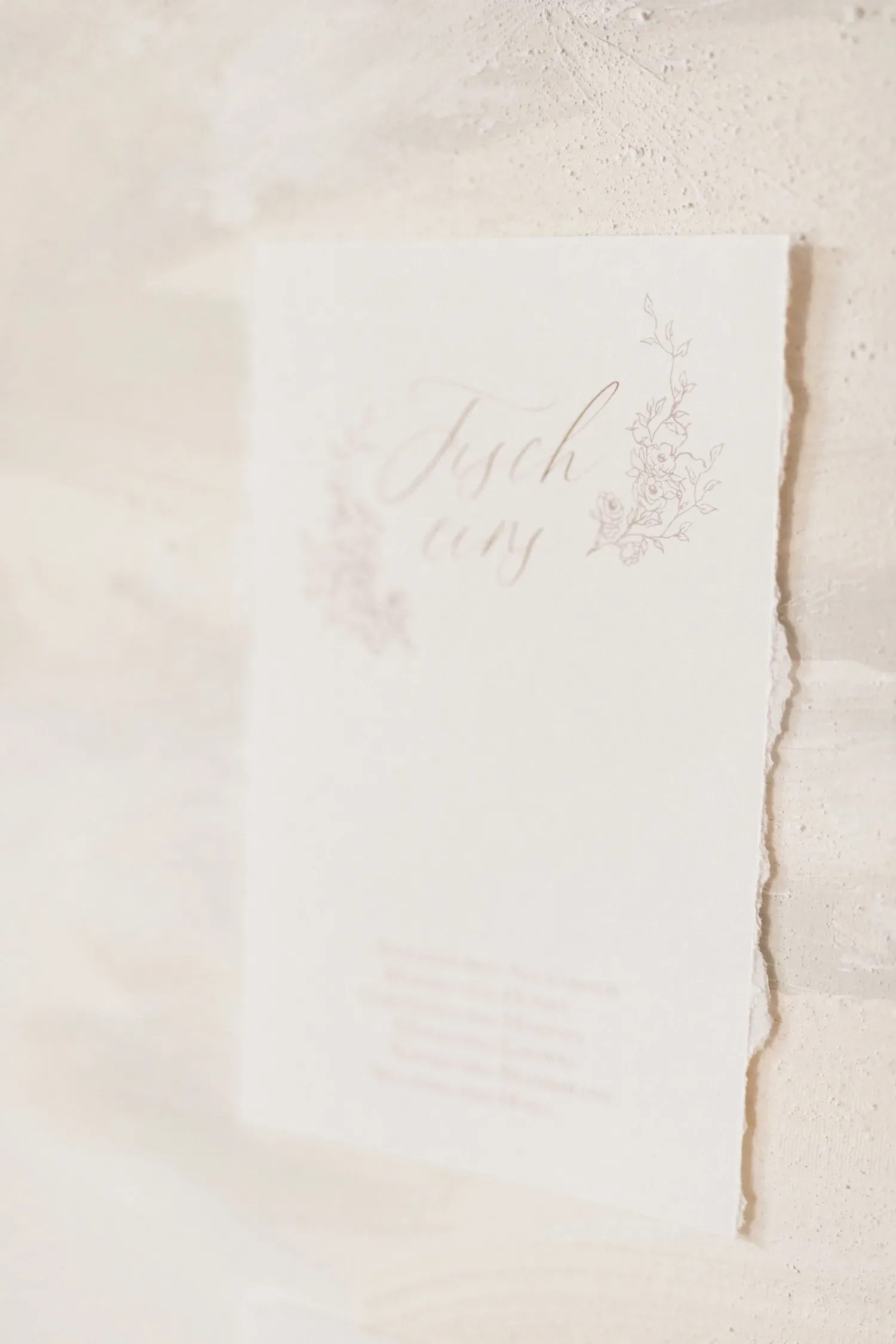 Ein edles Namensschild für den Sitzplan mit floralen Verzierungen und eleganter Schrift auf einem cremefarbenen Hintergrund.