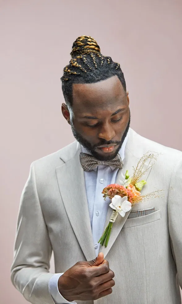 Bräutigam im hellen Anzug mit Fliege und farbigem Blumenanstecker, der elegant am Revers befestigt ist.