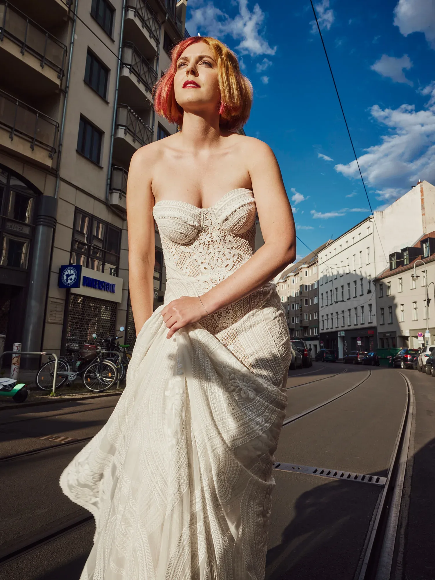 Braut im Hochzeitskleid mit rot gelb gefärbten Haaren posiert auf einer Straße