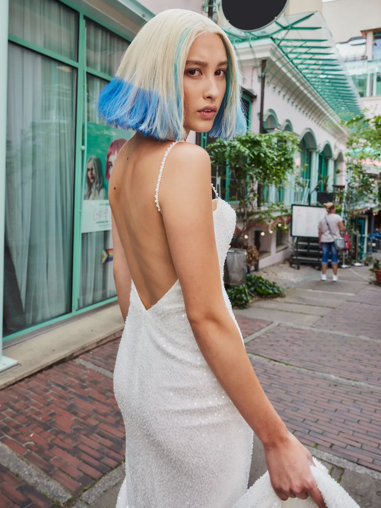 Braut im Hochzeitskleid mit blau blond gefärbten Haaren posiert auf einer Straße