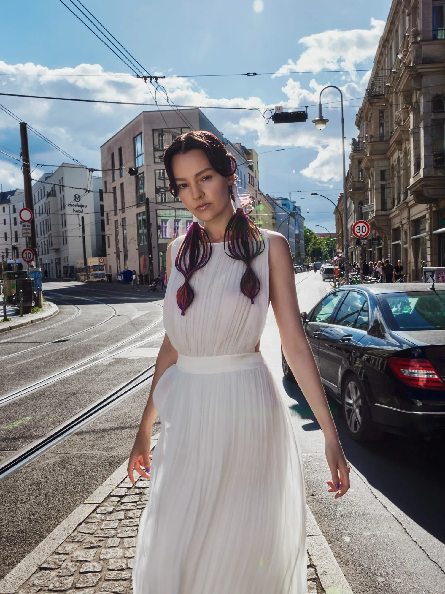 Braut im Hochzeitskleid mit bunt gefärbten Haaren posiert auf einer Straße