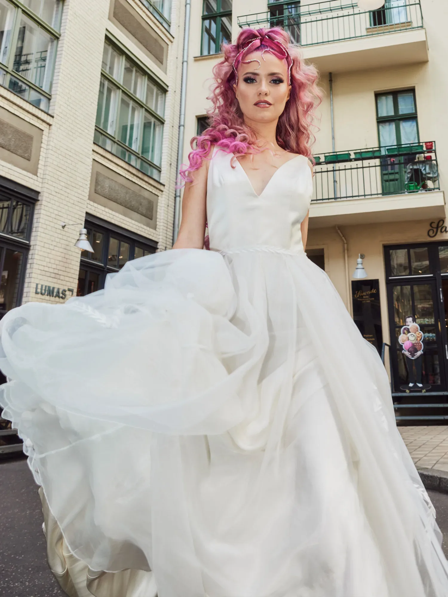 Braut im Hochzeitskleid mit rosa gefärbten Haaren posiert auf einer Straße