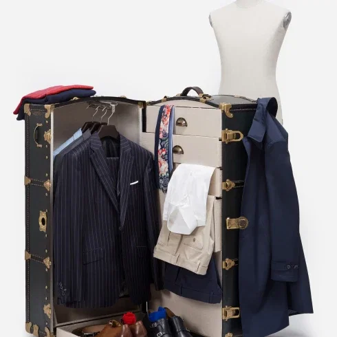 Ein geöffneter, luxuriöser Reisekoffer zeigt einen eleganten Anzug, Hemden und Accessoires, die ordentlich aufbewahrt sind, bereit für einen stilvollen Auftritt.