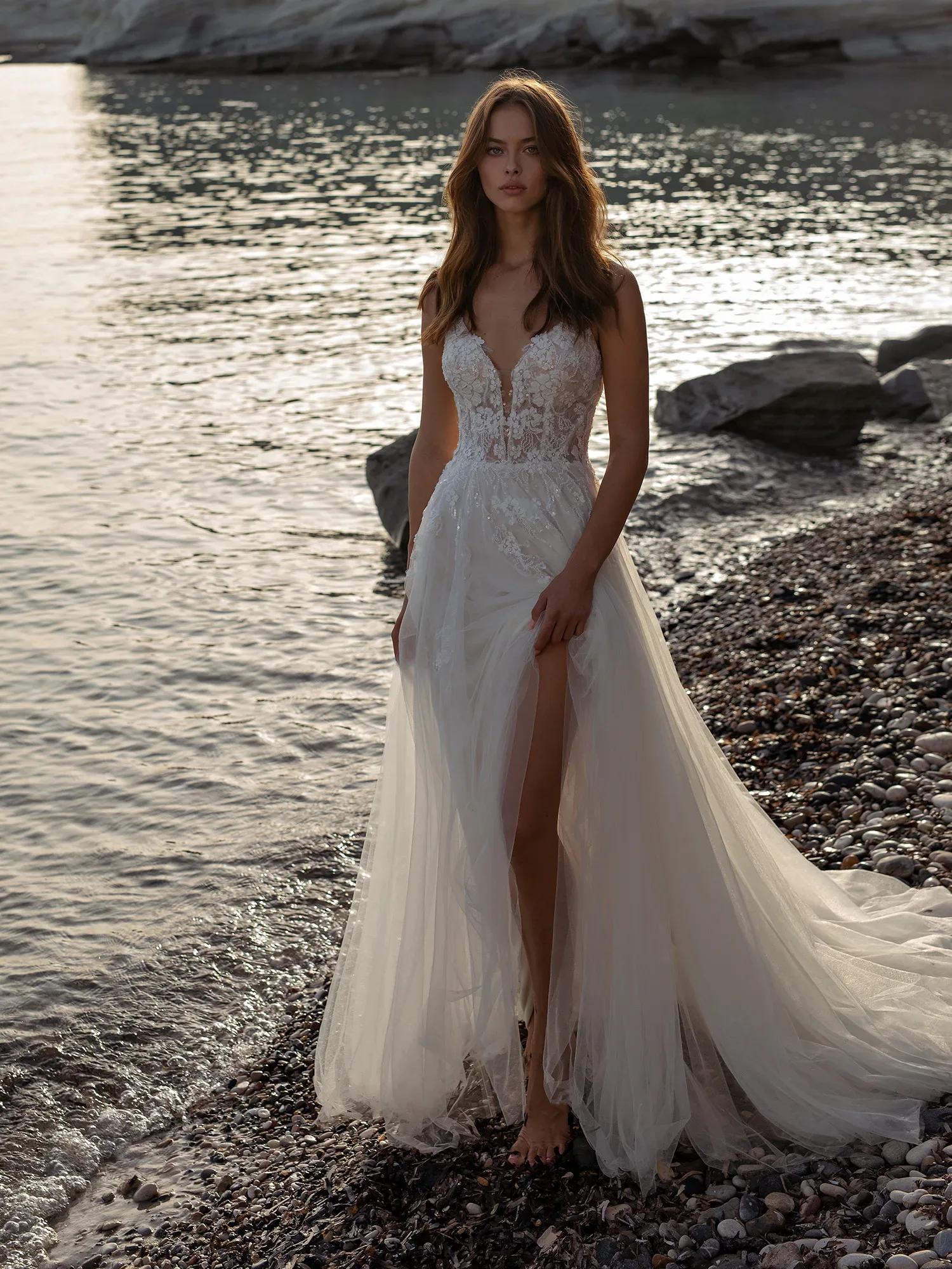 Braut im Hochzeitkleid aus Spitze mit Beinschlitz am Strand