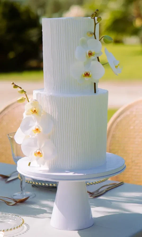 Hochzeitstorte in weiß mit seitlichen Blumenverzierungen.