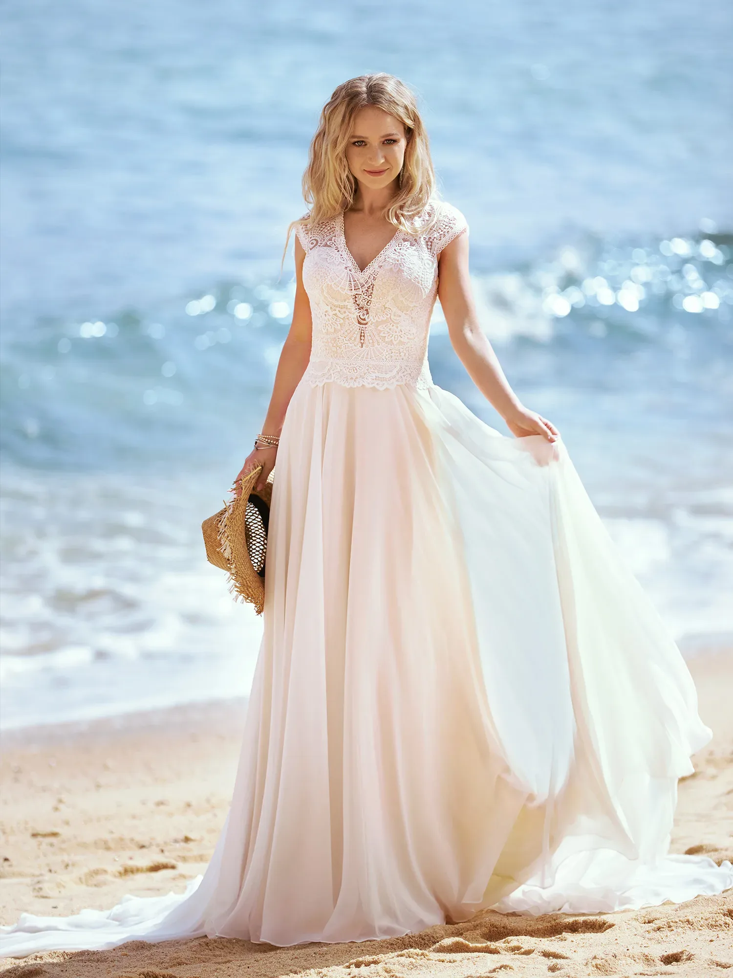 Braut im Brautkleid die Schleppe halten am Strand
