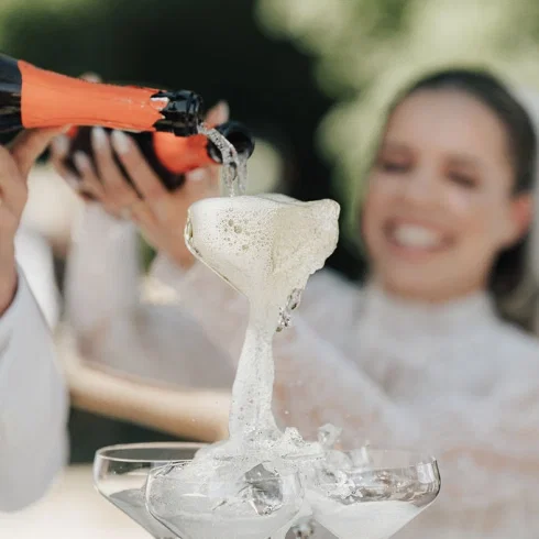 Braut und Bräutigam gießen Champagner in eine Glaspyramide, während der Schaum elegant über die Gläser fließt.