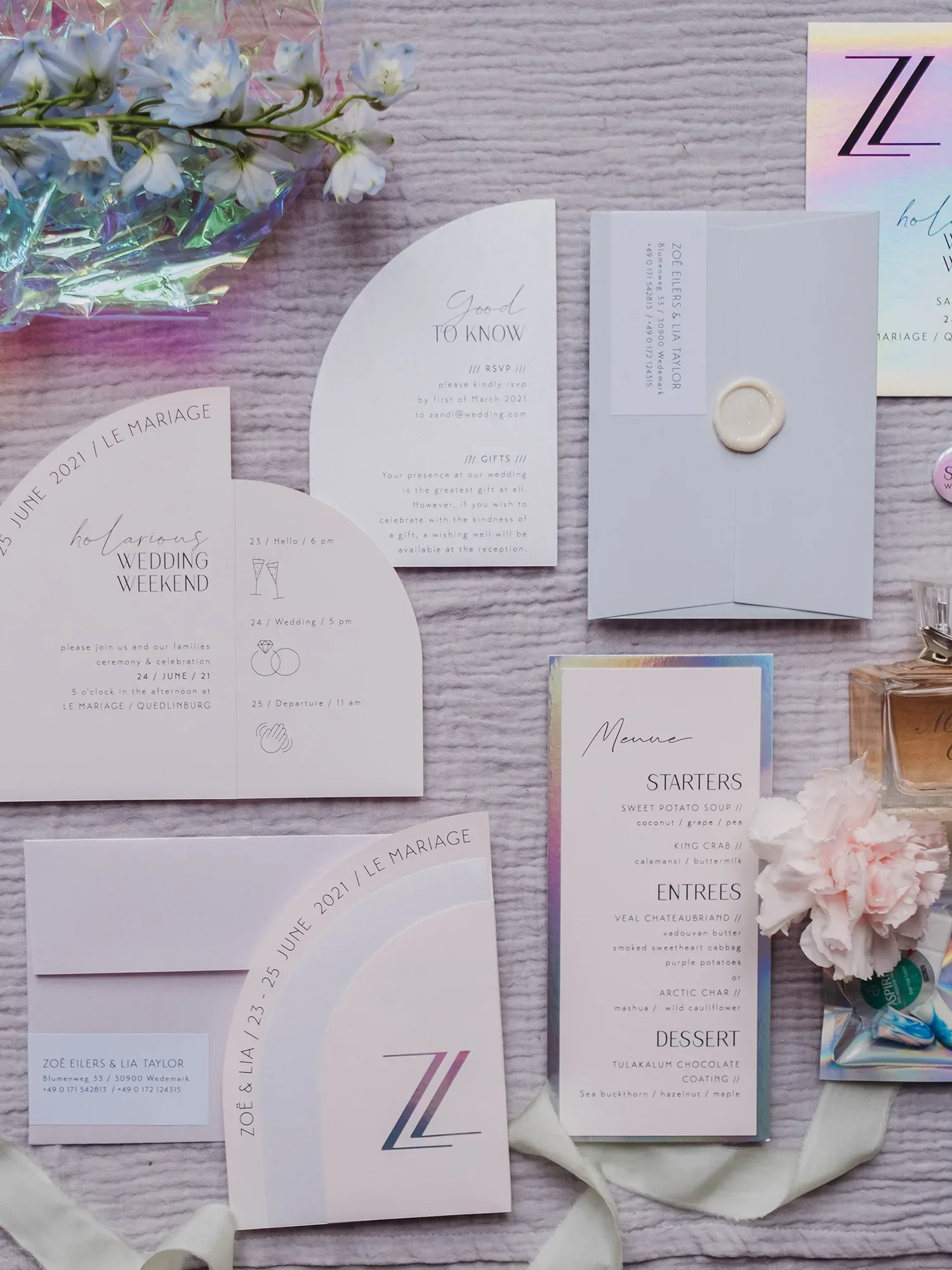 Flach gelegtes Set aus Hochzeitspapeterie: Einladungen, Menükarten und Informationskarten in einem modernen, minimalistischen Design mit schlichten Linien und eleganten Schriftarten. Neben den Karten liegt ein zartes Blumenarrangement aus weißen und blauen Blüten.