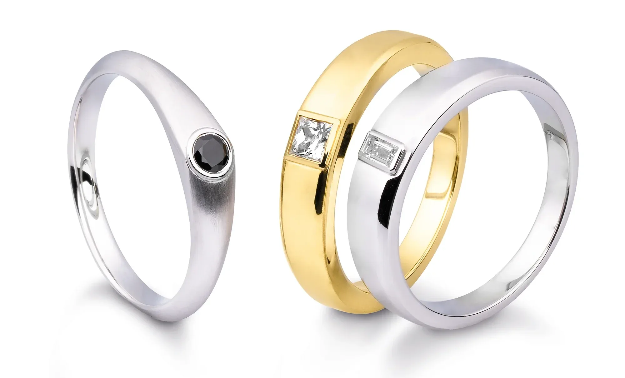 Drei elegante Eheringe in Gold und Silber. Zwei Ringe haben einen quadratischen Diamanten, während der dritte Ring einen runden schwarzen Stein trägt.