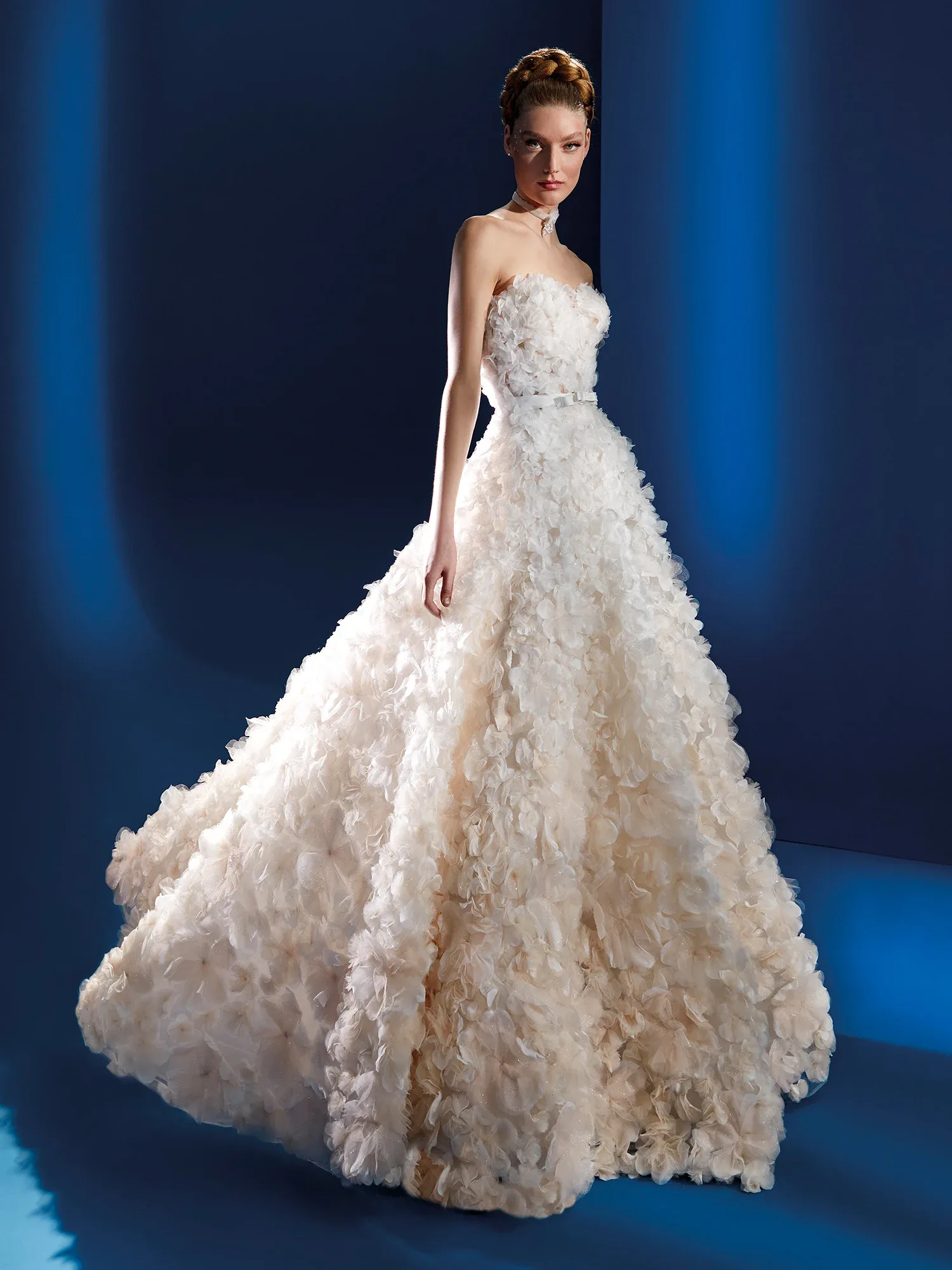 Vorderansicht eines voluminösen, trägerlosen Brautkleides mit aufwendigen Blütenapplikationen auf dem gesamten Kleid. Der üppige Rock und das strukturierte Design verleihen dem Kleid einen romantischen und dramatischen Look.