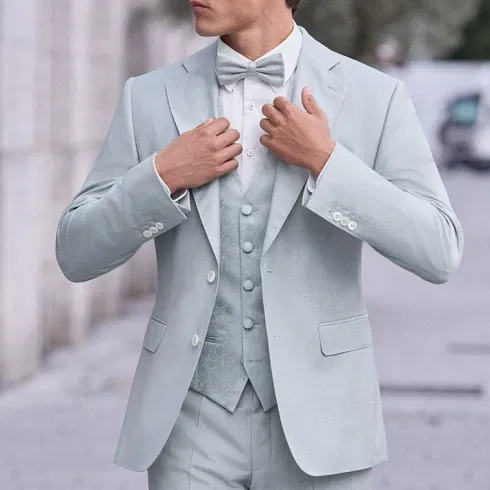 Nahaufnahme eines Bräutigams im hellmintfarbenen Anzug mit gemusterter Weste und Fliege.