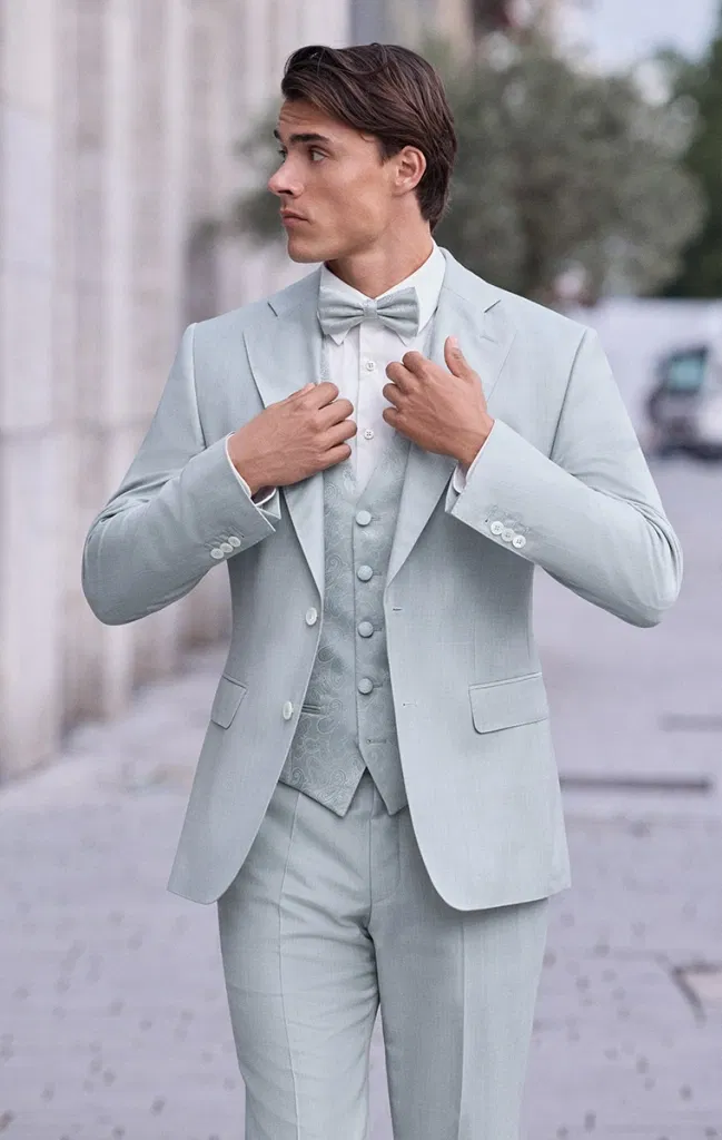 Nahaufnahme eines Bräutigams im hellmintfarbenen Anzug mit gemusterter Weste und Fliege.