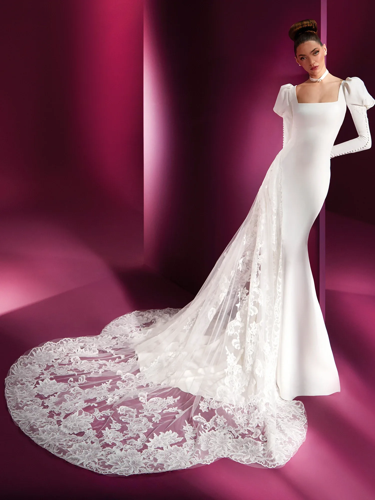 Brautkleid mit schmaler Silhouette und eckigem Ausschnitt, Vorderansicht. Das Kleid hat voluminöse Puffärmel und einen langen, aufwendig verzierten Spitzenschleier, der den Boden bedeckt.