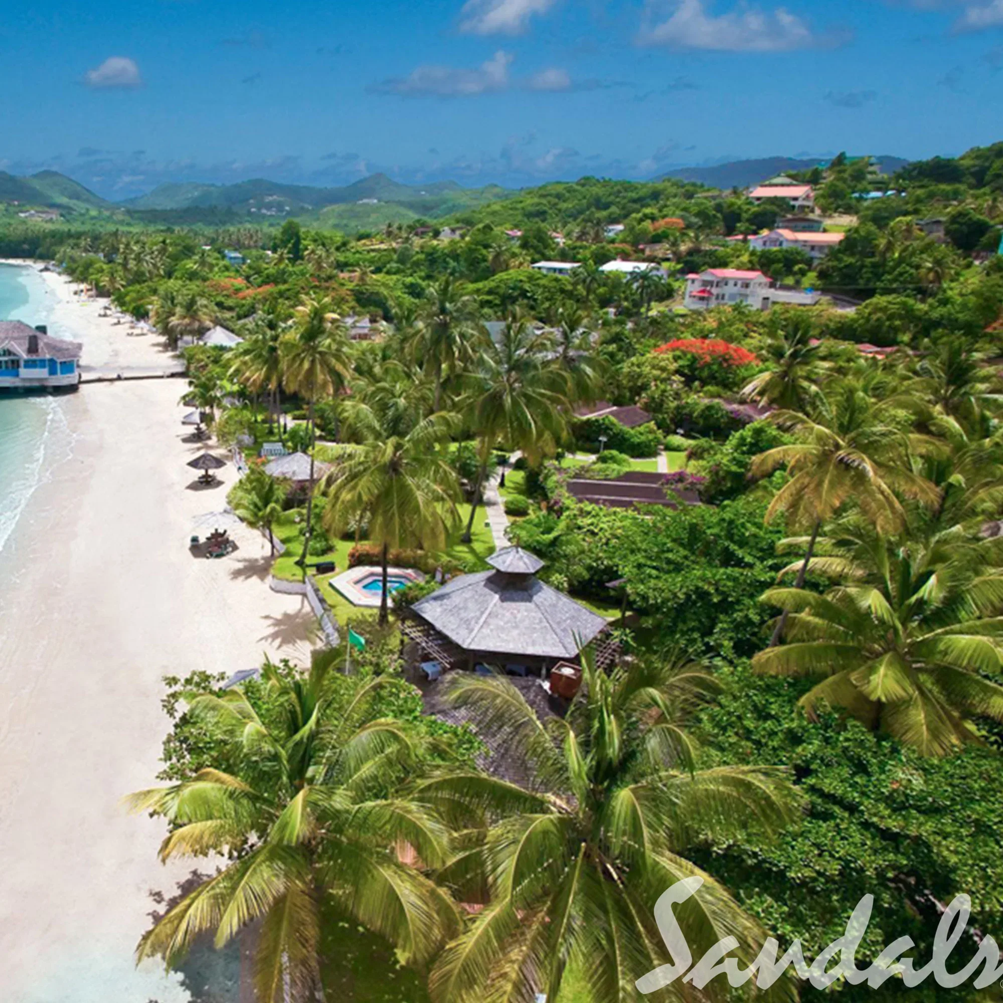 Ein tropisches Paradies auf St. Lucia, mit einer üppigen Landschaft aus Palmen und grüner Vegetation, die sich entlang des Strandes ausbreitet. Hütten und kleine Gebäude sind zwischen dem Grün und dem türkisblauen Meer verteilt.