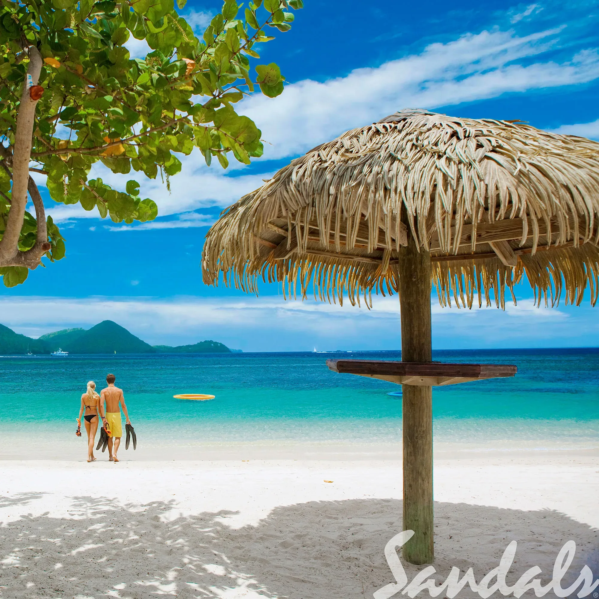 Ein idyllischer Strand auf St. Lucia, wo ein Paar am Ufer entlanggeht, bereit für einen Tag im Wasser mit Schnorchelausrüstung. Eine große Strohhütte und üppige Bäume umrahmen die Szene, die unter dem strahlend blauen Himmel stattfindet.