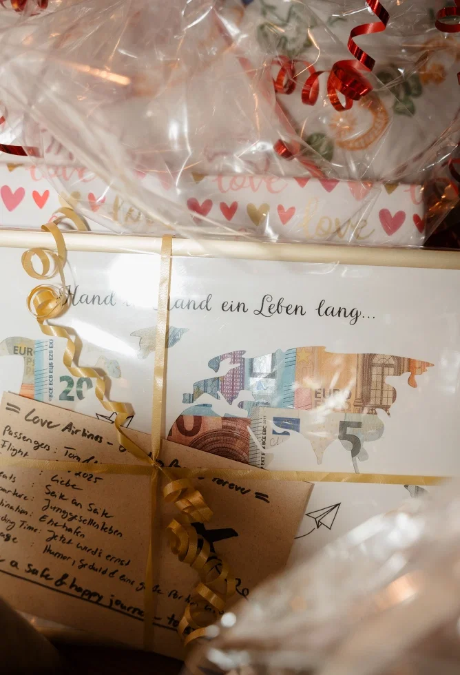 Liebevoll verpackte Hochzeitsgeschenke mit Geld, Schleifen und persönlicher Karte mit Reise-Motiv und Herzdesign