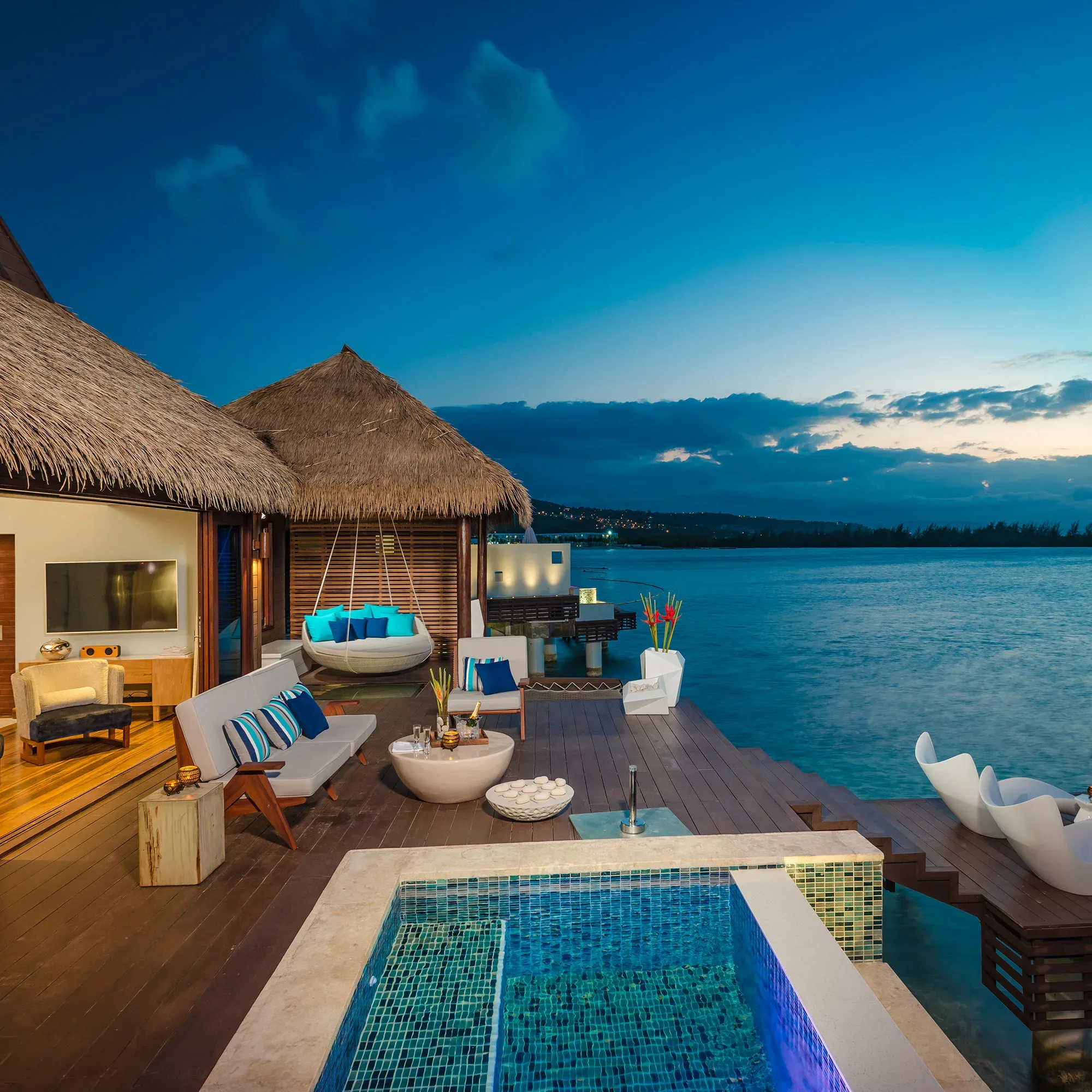 Ein luxuriöser Überwasser-Bungalow mit privatem Pool, gemütlicher Lounge und direktem Zugang zum Meer, während die Sonne untergeht.
