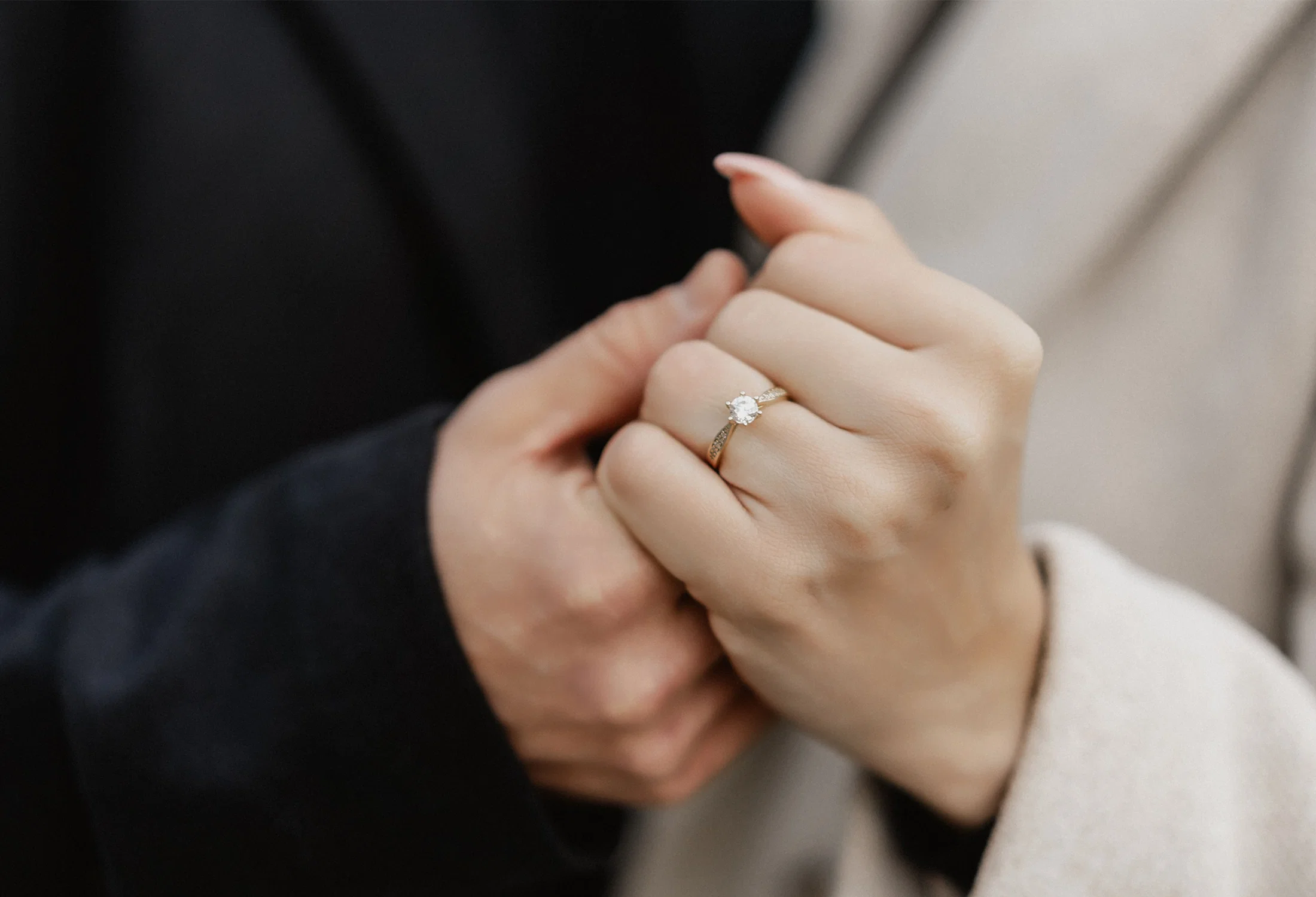 Frisch angesteckter Verlobungsring an der Hand der Frau, während das Paar sich nah gegenübersteht