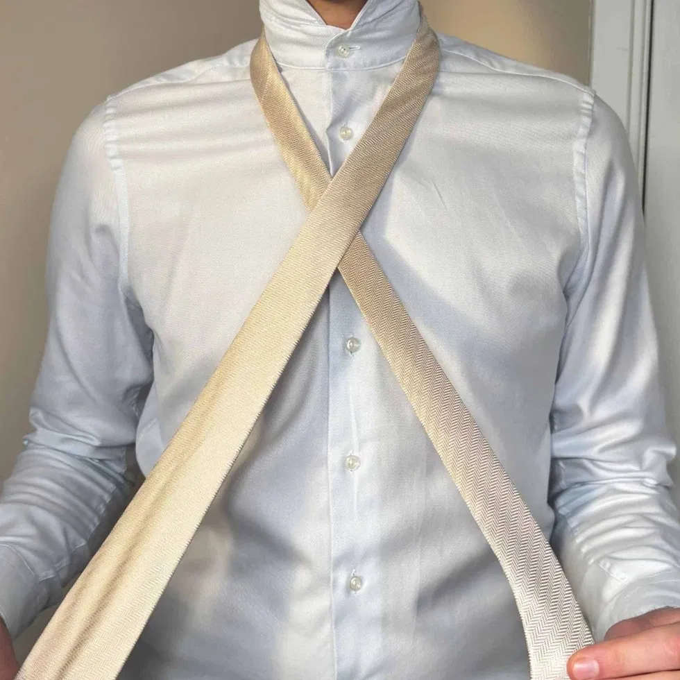 Die breite Seite der Krawatte wird über die schmale Seite gelegt, sodass sich ein X auf der Brust bildet.