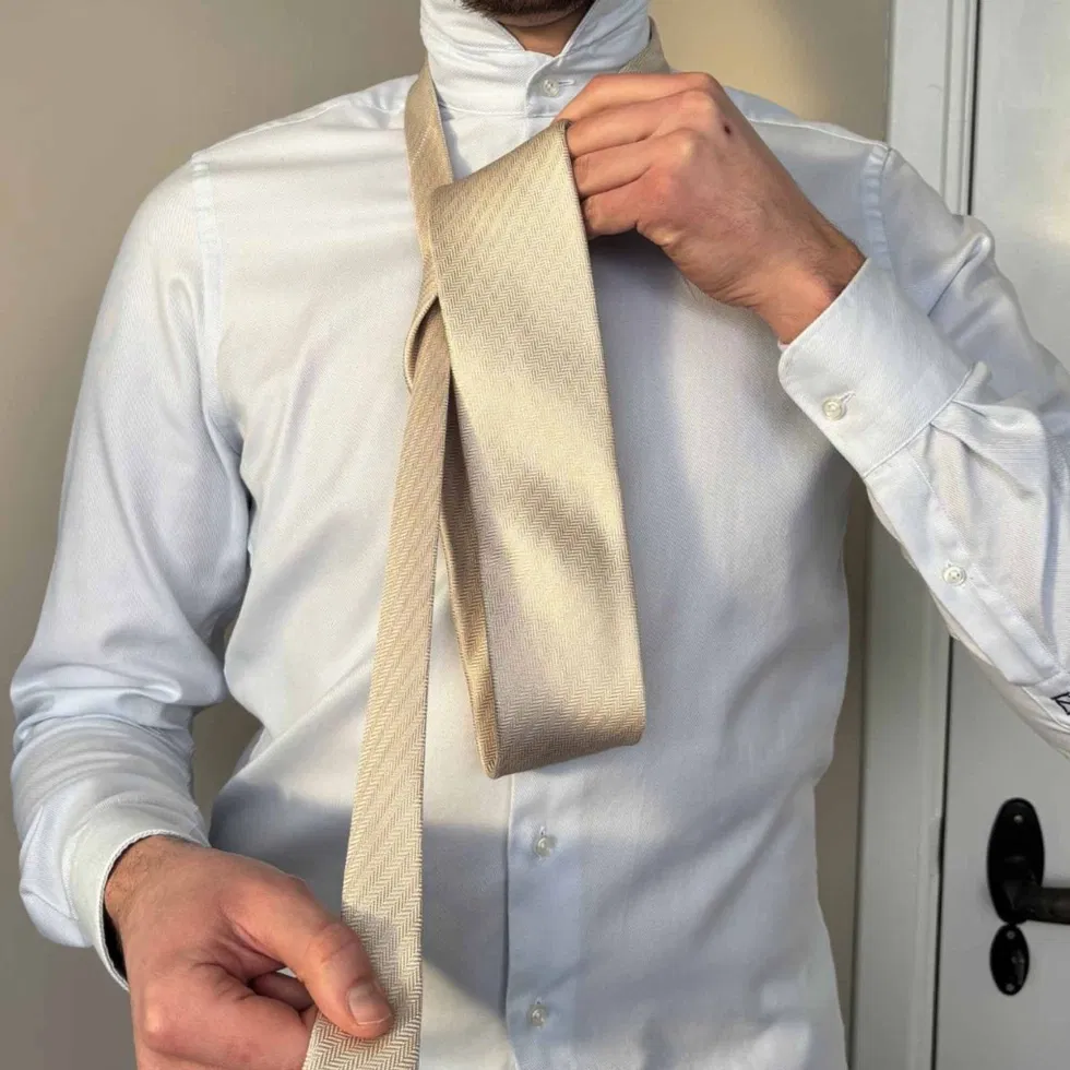 Die breite Seite der Krawatte wird erneut über die Vorderseite geführt, sodass eine Schlaufe entsteht.