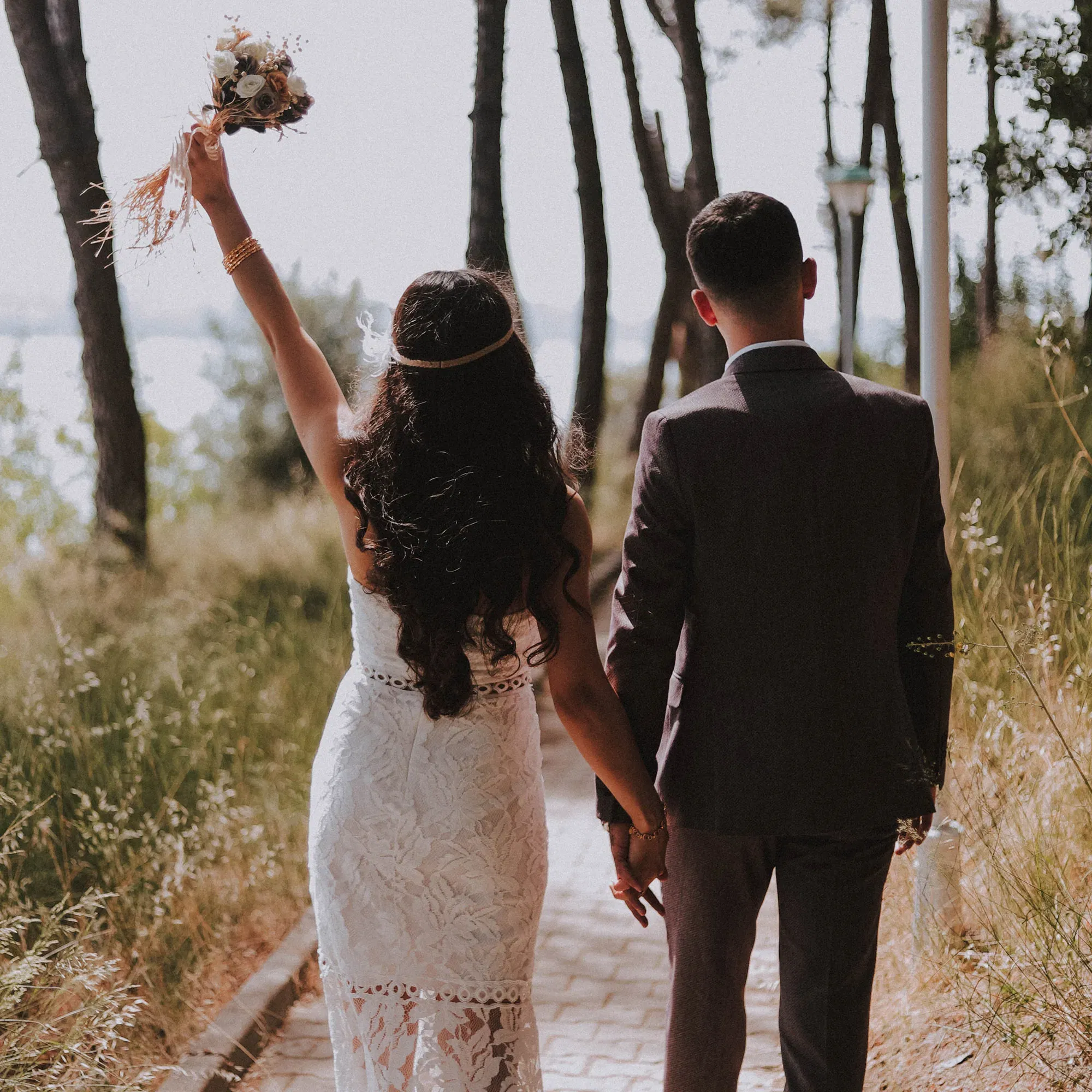 Brautpaar Rückenansicht, Braut hält ihren Brautstrauß in die Höhe.