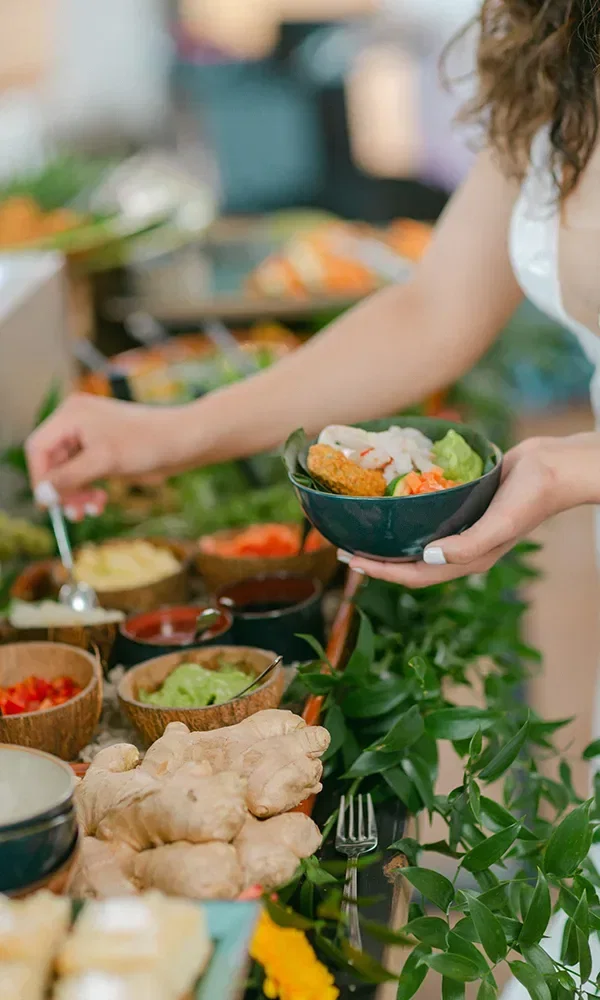 Verschiedene Gerichte werden auf einem tropisch gestalteten Buffet angeboten, mit frischem Gemüse, knusprigen Nachos und reichhaltigen Gewürzen, die alle auf grünen Pflanzenblättern arrangiert sind.