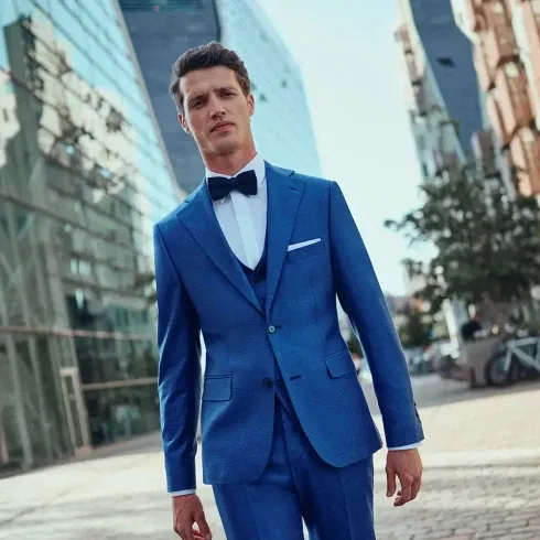 Ein Bräutigam in einem blauen Anzug mit dunkelblauer Weste und Fliege.