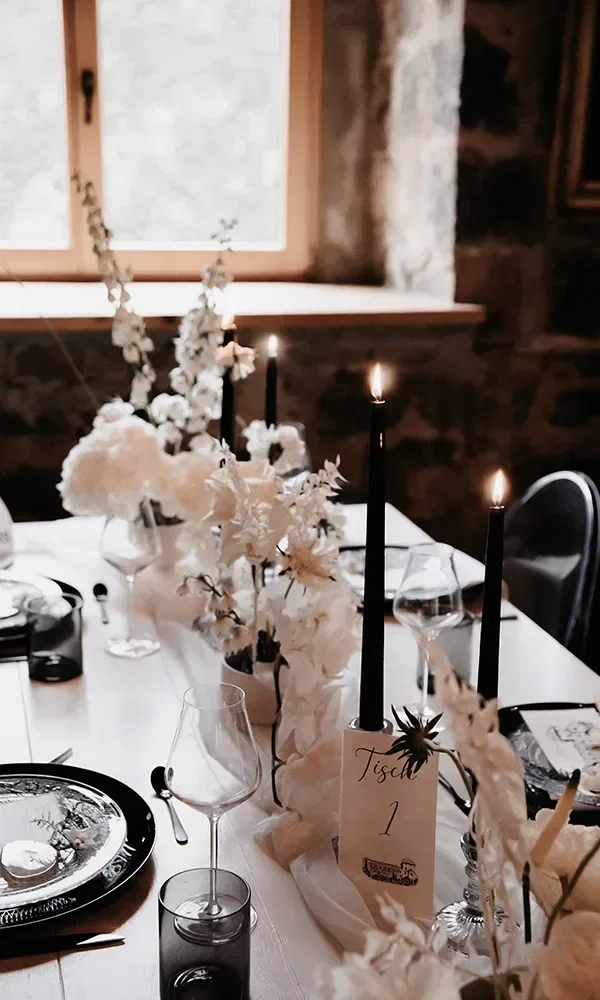 Table Setting mit schwarzen Kerzen und weißen Blumen