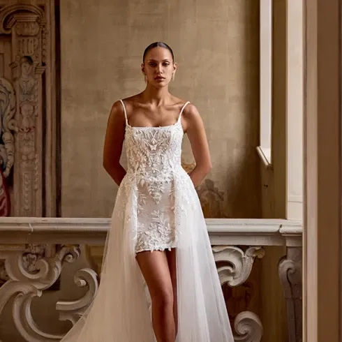 Spitzenkleid im Mermaid-Stil mit trägerlosem Ausschnitt, aufgenommen auf einer steinernen Treppe mit mediterranem Charme.