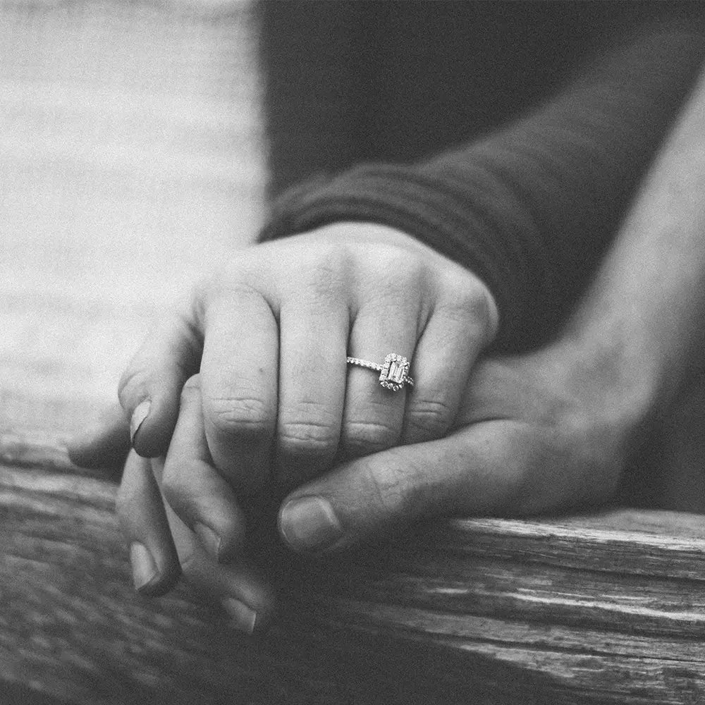 Die Hände eines Paares, die Hand der Dame mit einem Verlobungsring.