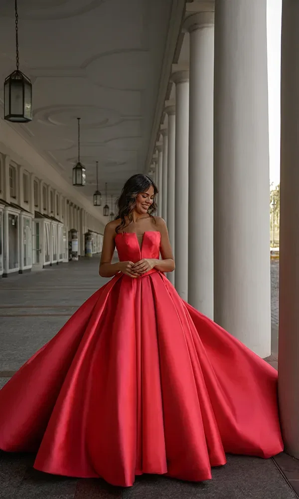 Eine Frau in einem opulenten, roten Samtballkleid mit einer Tiara, stehend vor einem historischen Fresko.
