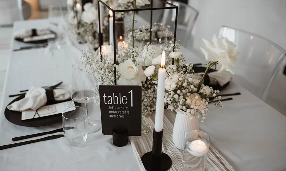 Schwarz-weiß gedeckter Hochzeitstisch mit weißen Blumenarrangements und schwarzen Kerzen