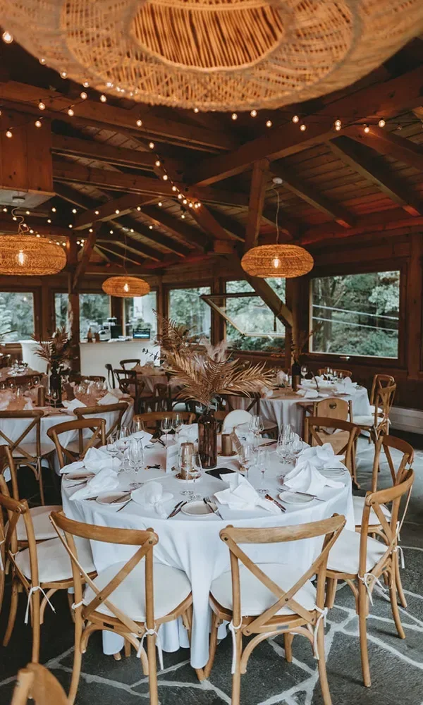 Boho-Hochzeitsdekoration mit weißen Tischdecken, Holzmöbeln und warmem Licht