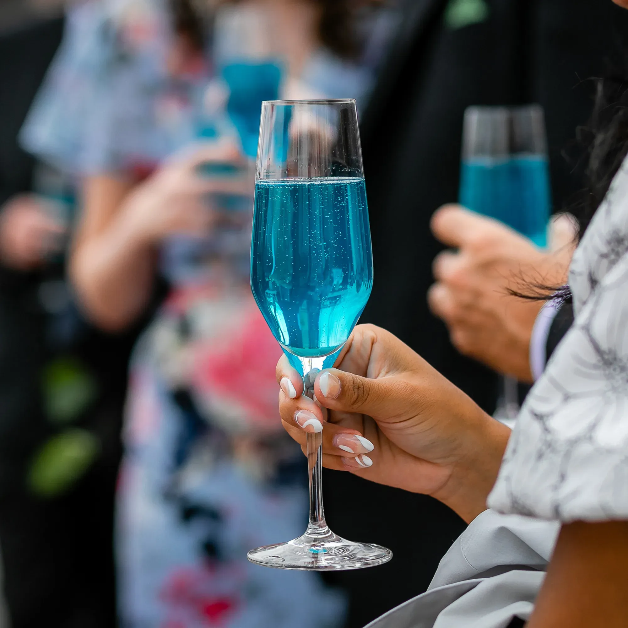 Hochzeitsgäste halten ein Blaues Aperitif.