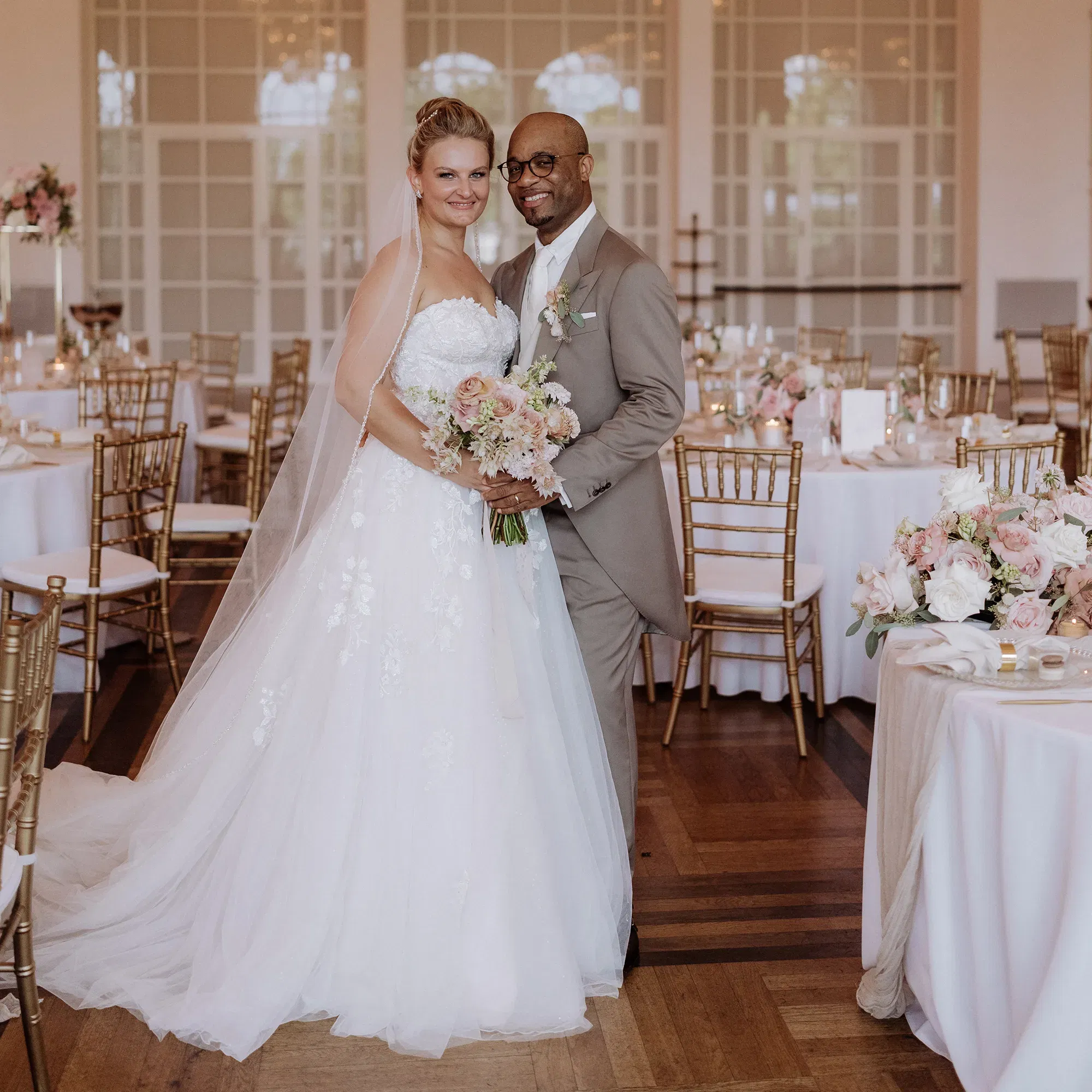 Brautpaar posiert im festlich geschmückten Festsaal.