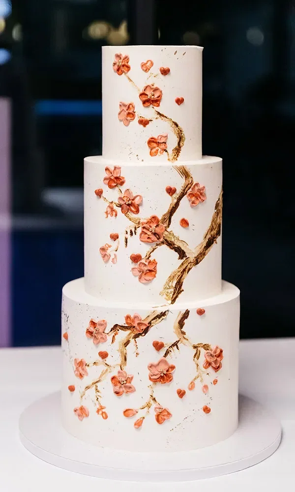 Weiße Hochzeitstorte mit aufgemalter Blumenverzierung.