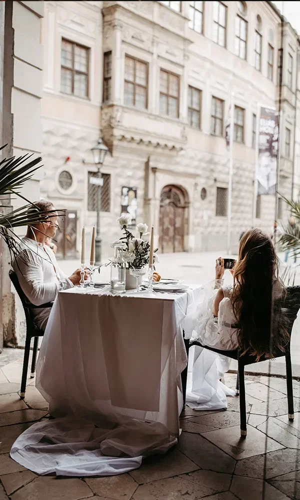 Ein paar sitzt in einem Café mit großer Glasfront und schaut raus.