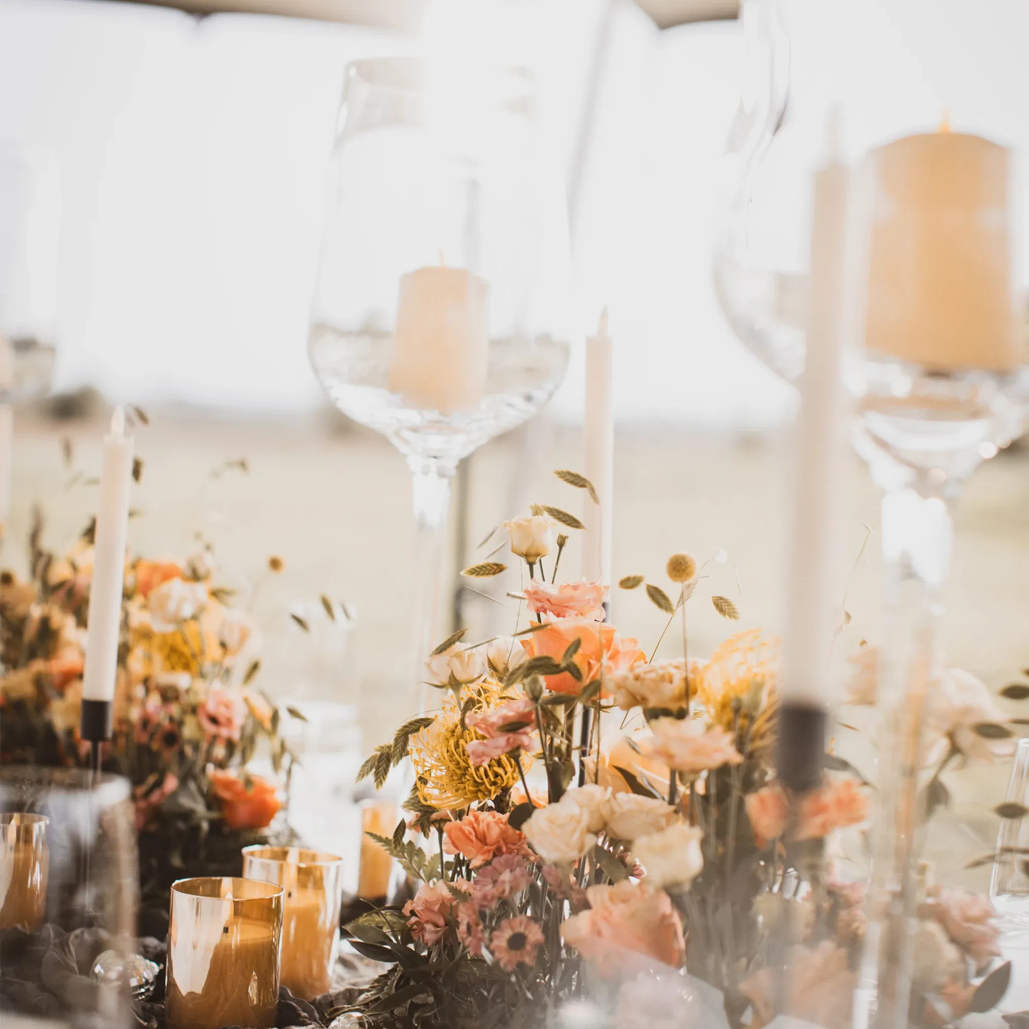 Ein elegant gedeckter Hochzeitstisch mit Blumen und Kerzen. Im Hintergrund erhellt die weiche Abendsonne die Szene.
